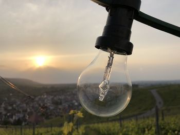 Close-up of light bulb on field against sky