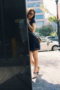 Portrait of woman standing on sidewalk in city