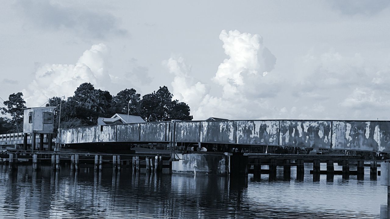 water, built structure, architecture, sky, waterfront, building exterior, cloud - sky, river, pier, railing, cloud, bridge - man made structure, connection, nature, reflection, day, lake, tree, tranquility, house