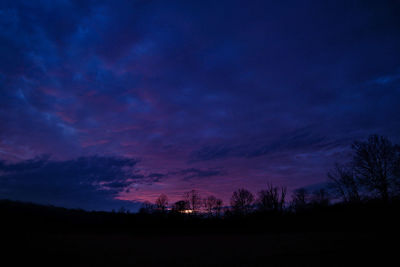 Silhouette trees on landscape against sky at night