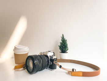 Camera and coffee cup on table in cafe background. style minimal.