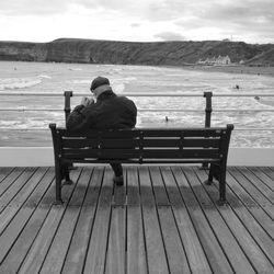 Man sitting on bench at beach