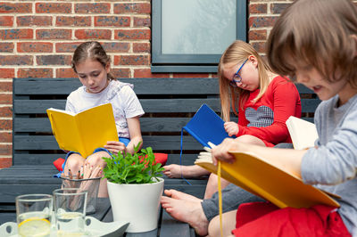 A group of friends from school sitting together in garden and doing homework.