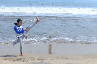 Full length of girl doing martial arts at beach