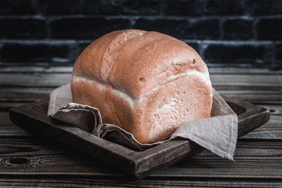 Square white bread in a wooden dish on the table.