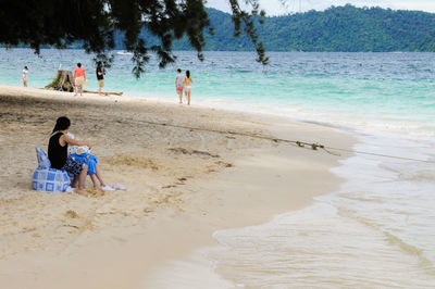 Rear view of two people sitting on beach