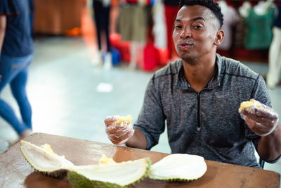 Portrait of man eating durian while sitting at table