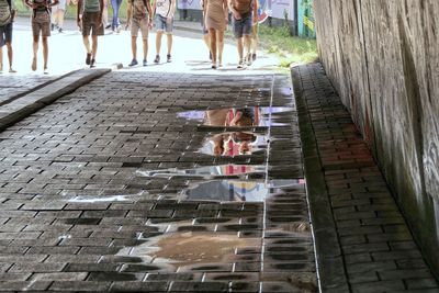 Low section of people walking on road in city