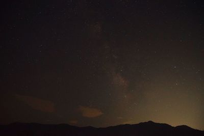 Silhouette mountain against star field at night