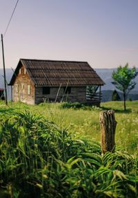 Wooden house on field against sky