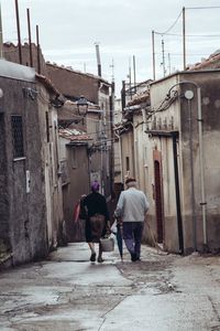 Rear view of men walking on street in city