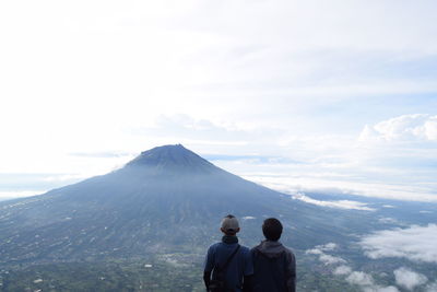 Rear view of people on mountain against sky