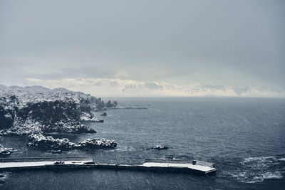 Snowy cliffs and pier at seaside in winter