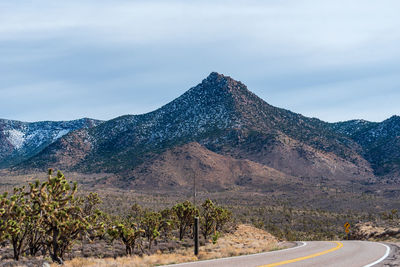 Road by mountains against sky