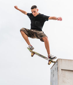 Full length of young man jumping against clear sky