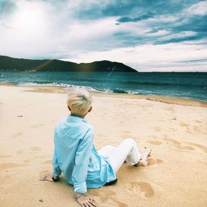 Rear view of man sitting on beach