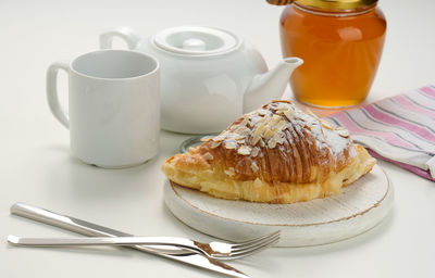 Baked crisp croissant is sprinkled with sugar powder and almond flakes on a wooden board, 