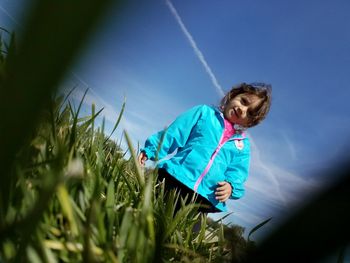 Portrait of girl standing on grassy field against sky