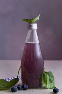 Non-alcoholic healthy organic bottle of drink with blueberries, seeds, basil extract, leaves. 