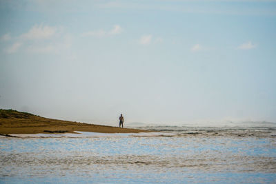 Man standing at beach against sky