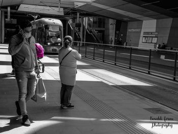 Rear view of people walking on railroad station