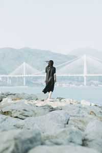 Rear view of man walking on mountain against clear sky