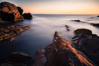 Rocks in sea during sunset