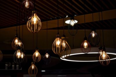 Low angle view of illuminated light bulbs hanging on table