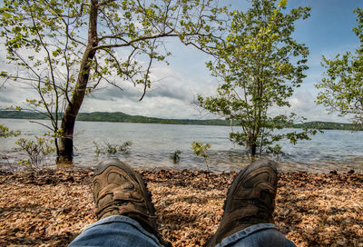 Low section of person by lake against trees