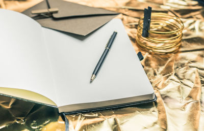 High angle view of blank book with pen on table