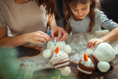 Midsection of mother and daughter knitting toy