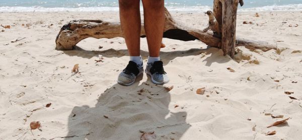 Low section of man standing on sand at beach