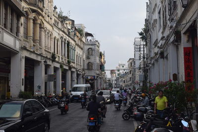 People on city street amidst buildings against sky