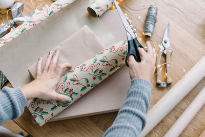 High angle view of woman wrapping christmas gift