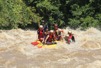 People in boat on river against trees