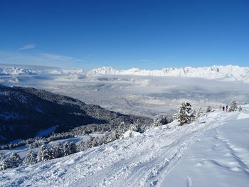 Scenic view of snow covered mountains against blue sky