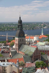 Buildings by bridge and river against sky on sunny day