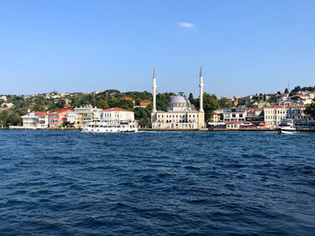 Sea by buildings against sky in city