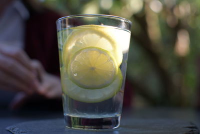 Close-up of lemon slices and drink in drinking glass on table outdoors