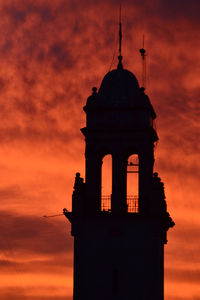 Low angle view of silhouette building against orange sky