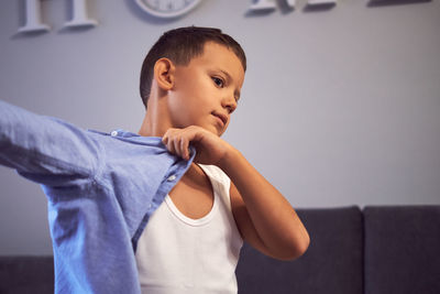 Portrait of boy standing against wall