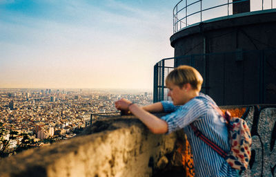 Side view of man looking at city buildings