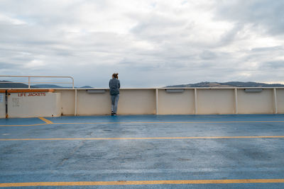 Rear view of man standing on road against sky