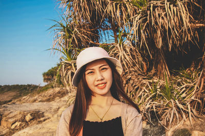 Portrait of young woman wearing hat standing against plants