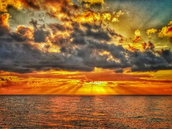 Scenic view of sea against dramatic sky during sunset