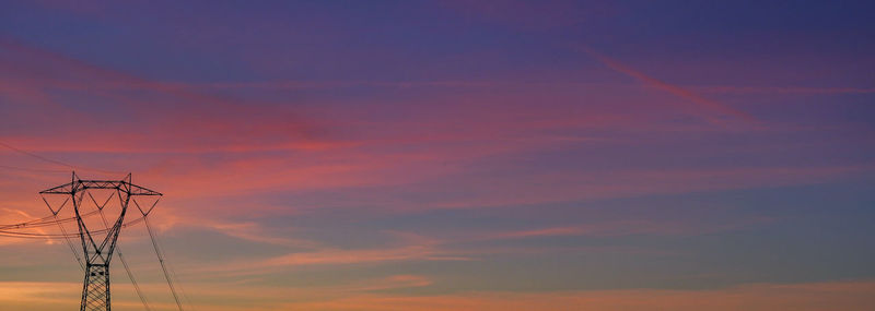 Low angle view of silhouette electricity pylon against sky during sunset