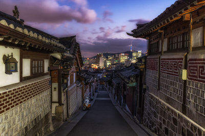 Road amidst houses in city during sunset