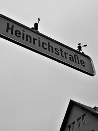 Low angle view of signboard in city against clear sky