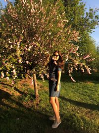 Portrait of young woman standing by tree