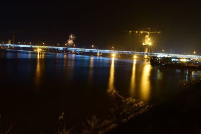 Illuminated bridge over river at night